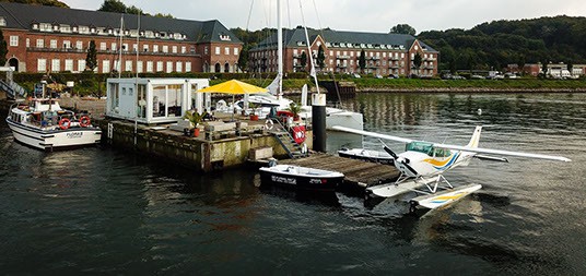 Drohnenbild der Wasserflugstation in Flensburg mit Wasserfluzeug und den Booten aus dem Bootsverleih.